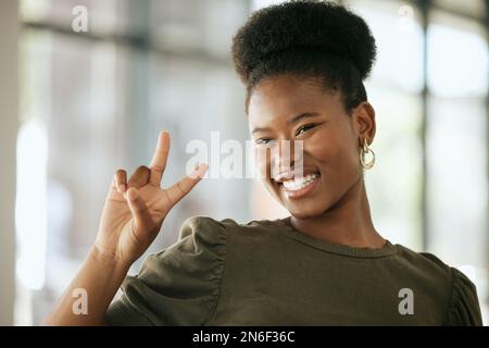 Happy optimistic african american business woman gesturing peace. Playful young female entrepreneur showing victory sign in an office Stock Photo