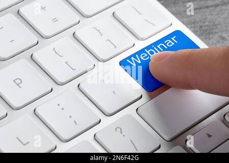 Online learning. Woman pressing button on computer keyboard with word Webinar, closeup Stock Photo