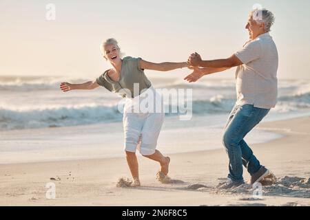 Cheerful mature couple playing on the beach. Senior couple having fun on the beach together. Happy senior couple being carefree by the ocean together Stock Photo