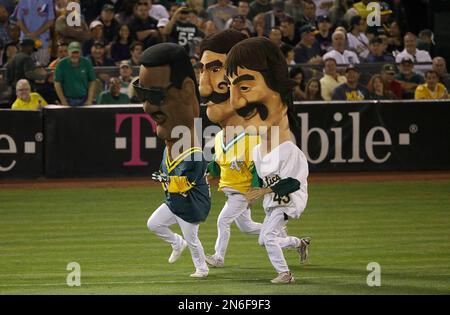 Mascots representing former Oakland Athletics Rollie Fingers, from left,  Dennis Eckersley and Rickey Henderson wait before racing during a baseball  game between the Athletics and the New York Yankees in Oakland, Calif.