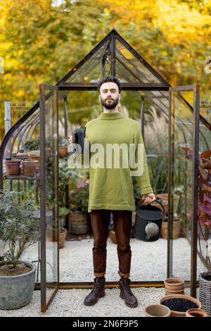 Stylish guy with watering can in garden Stock Photo