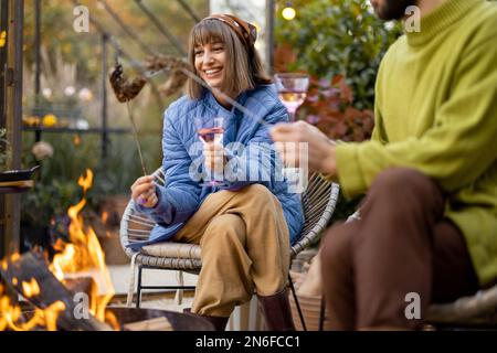 Young couple spending dinner time by the fire at backyard Stock Photo