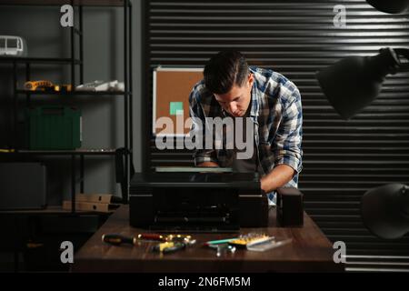 Professional repairman fixing modern printer in office Stock Photo