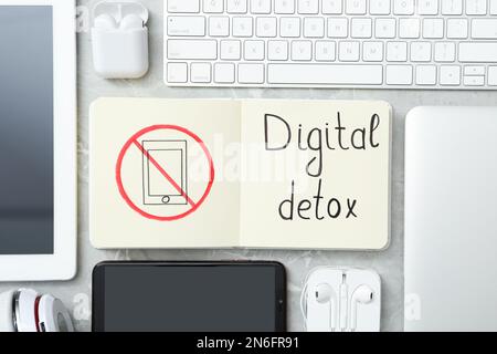 Flat lay composition of gadgets and notebook with words DIGITAL DETOX on light grey marble background Stock Photo