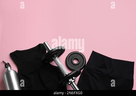Sportswear, water bottle and dumbbell on pink background, flat lay with space for text. Gym workout Stock Photo