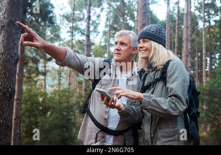 Finding our way with the help of a digital compass. a mature couple using a cellphone while out on a hike together. Stock Photo