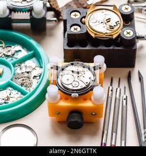old watches in holders and tools on wooden table in watchmaker workshop Stock Photo