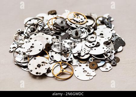 pile of old spare-parts for mechanical clocks closeup on wooden table in watchmaker workshop Stock Photo