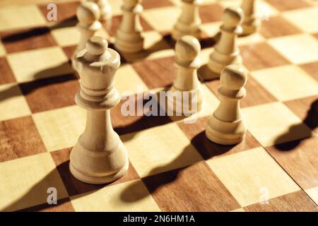 Queen and pawns on wooden chess board, closeup. Social roles concept Stock Photo