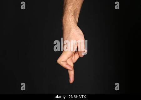 Man imitating walk with hand on black background, closeup. Finger gesture Stock Photo