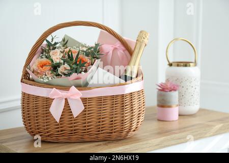 Wicker basket with gifts on table indoors Stock Photo