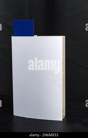 Blank white book cover template with blue bookmark on top of the black speaker cabinet . Clipping path. Stock Photo