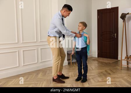 Father helping his little child get ready for school in hallway Stock Photo