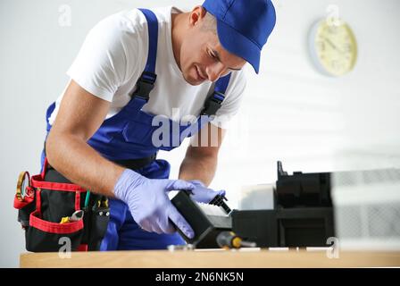 Professional repairman fixing modern printer in office Stock Photo
