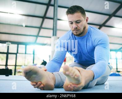 Gymnastics, exercise or man stretching legs in gym before training, workout or health wellness. Focus, serious fitness or sport athlete doing pilates Stock Photo