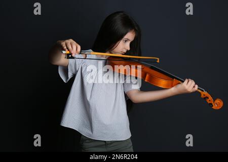 Preteen girl playing violin on black background Stock Photo - Alamy