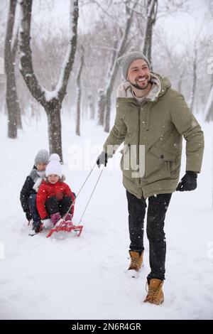 Father sledding his children outside on winter day. Christmas vacation Stock Photo