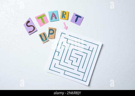 Sheets of paper with words Start Up and maze on white background, flat lay Stock Photo