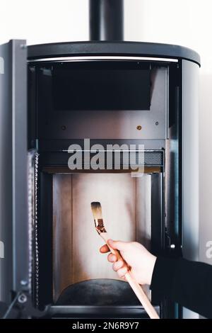 Man cleaning pellet stove with brush Stock Photo