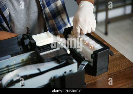 Professional repairman fixing modern printer indoors, closeup Stock Photo