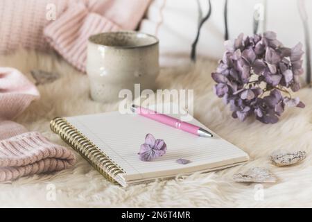 Cozy coffee break scene with notebook, cup and wool fabric, cream and lilac colors Stock Photo