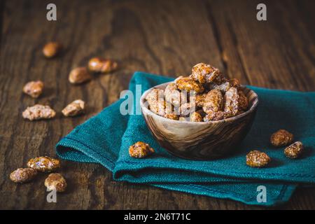 Bowl of sweet candied almonds on rustic wooden background Stock Photo