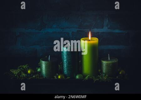 Advent wreath with four different candles in green colors on dark background, christmas decoration, copy space Stock Photo