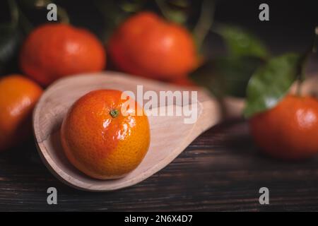 Fresh tangerines with leaves on a wooden spoon, selective focus Stock Photo