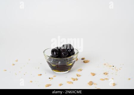 Top view of black olives marinated with olive oil in glass bowl isolated on white background. Stock Photo