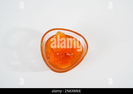 Homemade peach jam in small glass bowl isolated on white background. Stock Photo