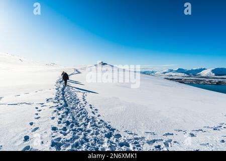 Tourists walking a hiking trail at the top of Storsteinen mountain in Tromso, Norway, on a sunny winter day Stock Photo