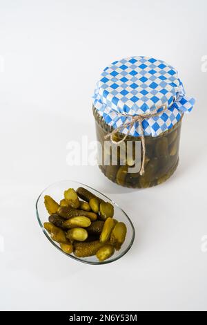 Top view of cucumber pickles jar and sliced pickled gherkins on glass plate isolated on white background. Stock Photo