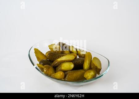 Top view of sliced pickled gherkins on glass plate isolated on white background. Stock Photo