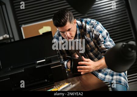 Professional repairman fixing modern printer in office Stock Photo
