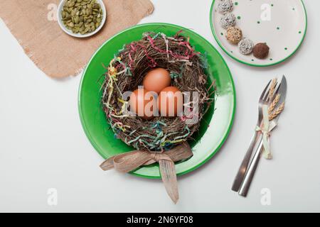 nest with eggs on green plate. Happy Easter. Stylish white table, flat lay. Natural eggs spring Stock Photo