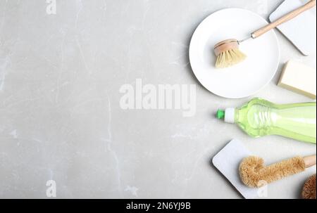 Flat lay composition with cleaning product and tools on grey table, space for text. Dish washing supplies Stock Photo