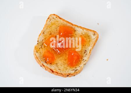 Slice of bread with apricot jam isolated on white background. Stock Photo