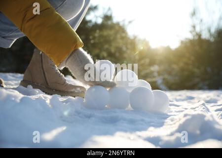 Woman rolling snowballs outdoors on winter day, closeup Stock Photo