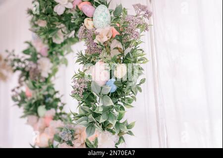 happy easter and spring holidays time. easter wreath with sprigs of lilac bush blossom flowers and leaves and decorated colorful eggs on bright light Stock Photo