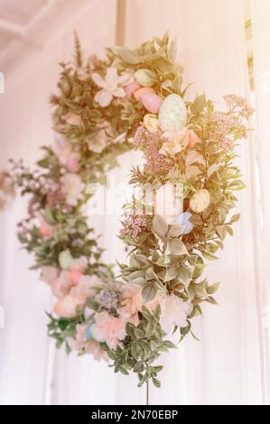 happy easter and spring holidays time. easter wreath with sprigs of lilac bush blossom flowers and leaves and decorated colorful eggs on bright light Stock Photo