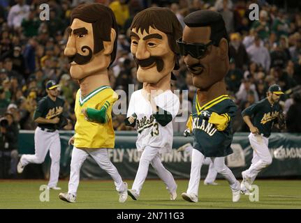 Mascots representing former Oakland Athletics Rollie Fingers, from left,  Dennis Eckersley and Rickey Henderson wait before racing during a baseball  game between the Athletics and the New York Yankees in Oakland, Calif.