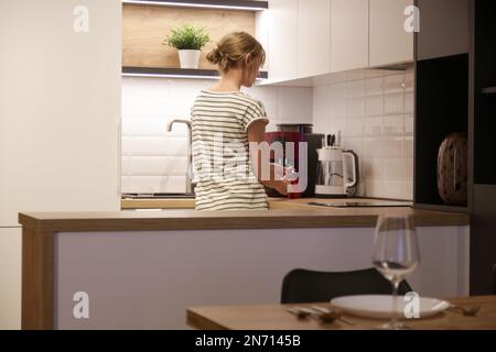 Woman making fresh espresso in coffee maker. Woman preparing big mug of coffee at home. Stock Photo