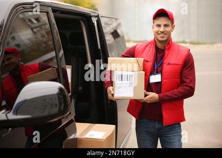 Courier with parcels near delivery van outdoors Stock Photo