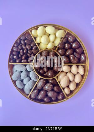 Overhead view of a box of assorted chocolates against a purple background Stock Photo
