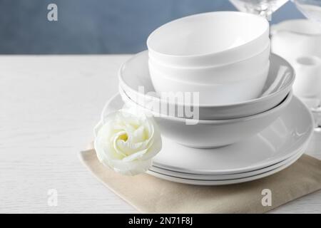 Dishware, napkin and eustoma flower on light table, space for text Stock Photo
