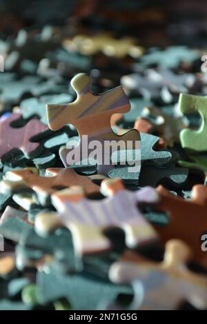 Jigsaw Puzzle Pieces In A Pile All Together - Piece Of Puzzle Standing Upright Facing Towards You - UK Stock Photo
