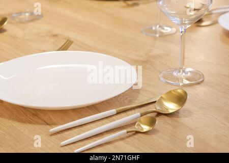 Dining table arrangement with white ceramic plates, silver flatware set with white handles and wine glasses Stock Photo