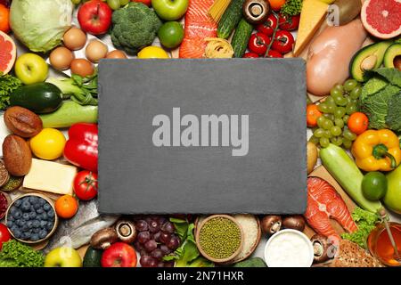 Slate board on pile of different food products, top view with space for text. Healthy balanced diet Stock Photo