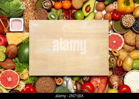 Wooden board on pile of different food products, top view with space for text. Healthy balanced diet Stock Photo