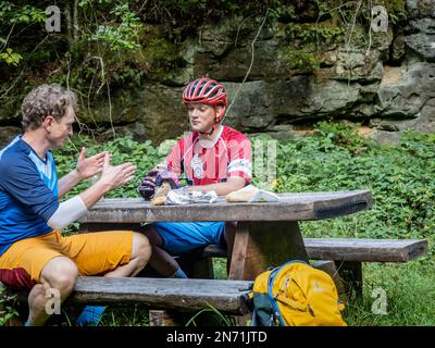 E-mountain bikers in the Grengewald (Grünewald) near Luxembourg City taking a rest on one of the main paths that the Romans had laid out in Luxembourg. Stock Photo